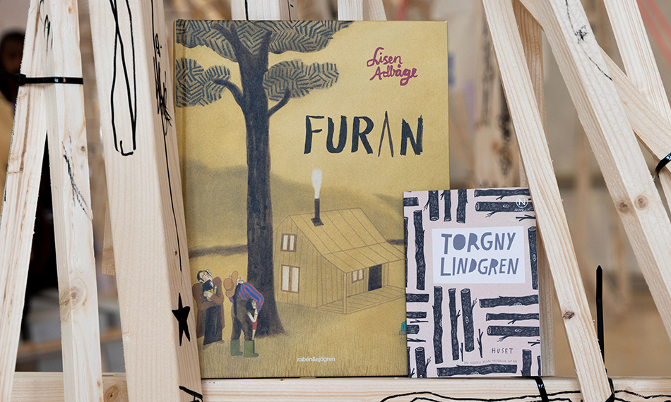 Böckerna "Furan" av Lisen Adbåge och "Huset" av Torgny Lindgren står bland träpinnarna i utställningen BYGGET i konsthallen.