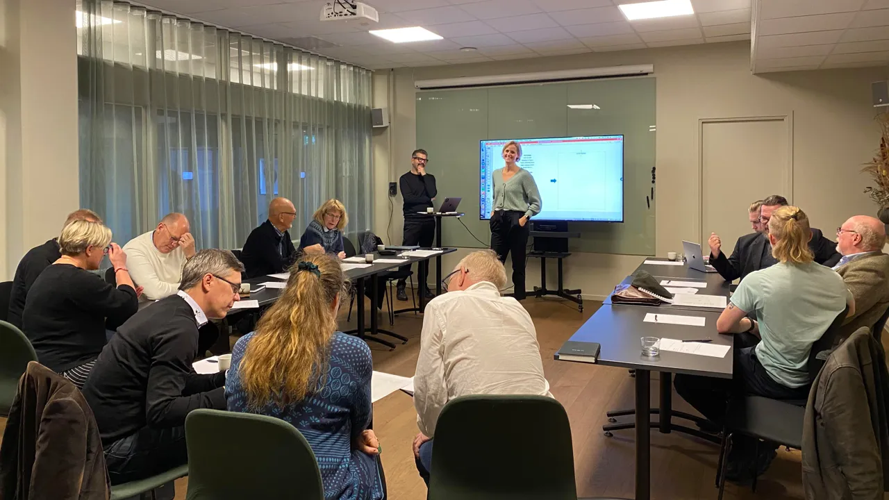 En grupp människor som sitter runt bord i ett rum.