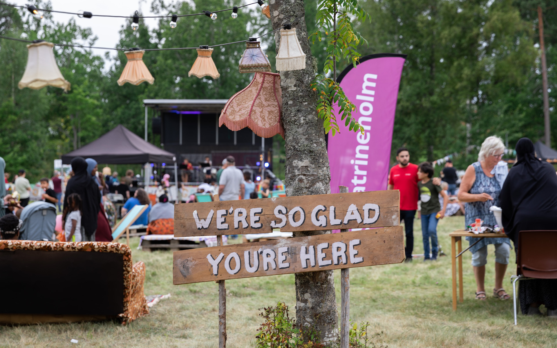 Gatufest i Nävertorp 2022. Människor är samlade på en gräsplan med en stor scen, mat och aktiviteter.