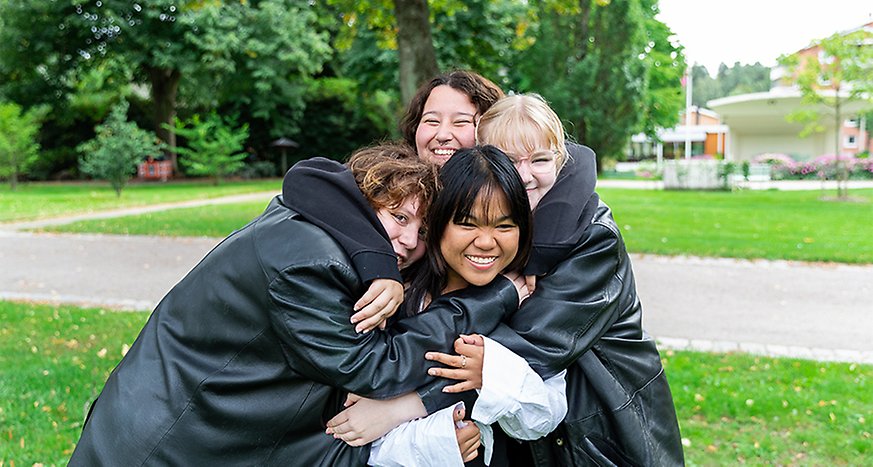 Fyra personer som kramar varandra och skrattar. Det står i Stadsparken i Katrineholm.
