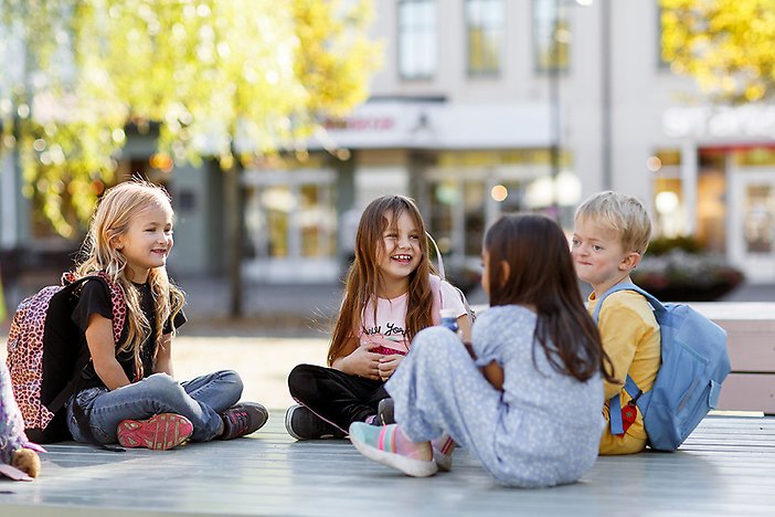 Fyra barn sitter i en central miljö och pratar och skrattar